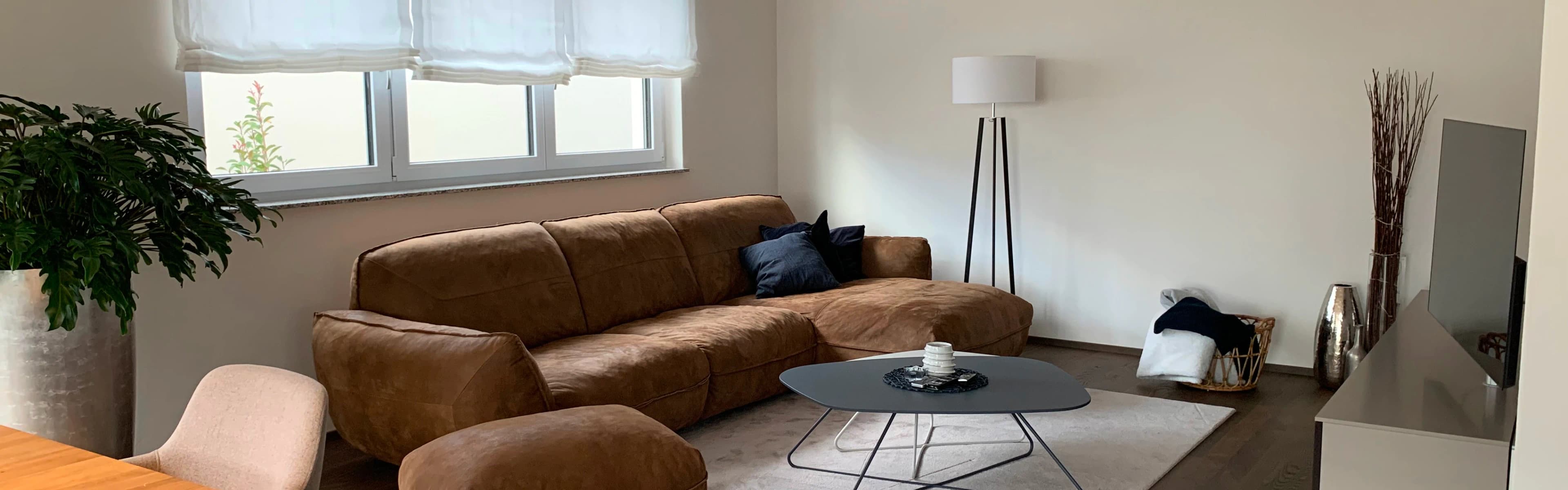 Wohnzimmer mit brauner Couch und edlem Beistelltisch und Lampe